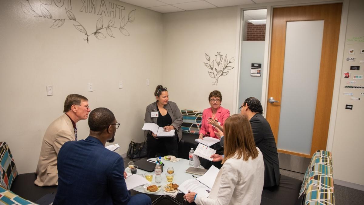 Entrepreneurship faculty gather around a small table 